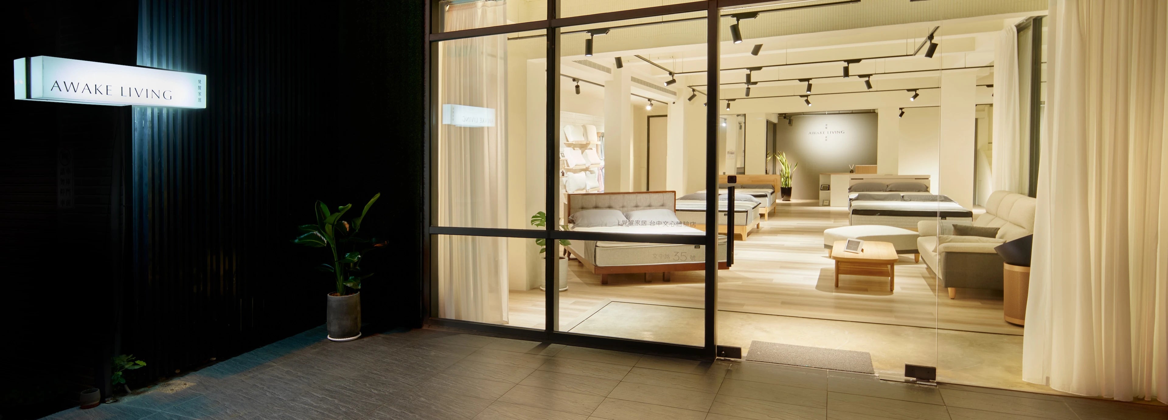 Awake Living 台中文心體驗店門市的夜間全景,可從店外看見內部寬敞明亮的床墊展示區。
