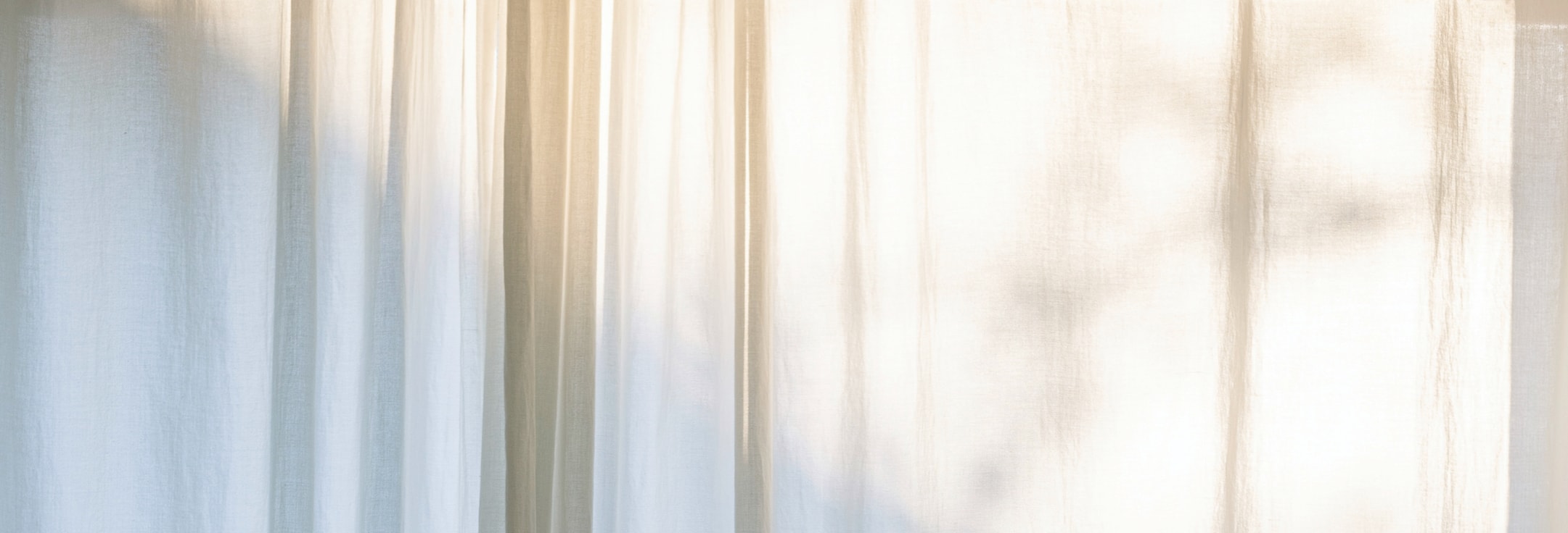 陽光灑落到樹葉上映射其陰影到窗簾上