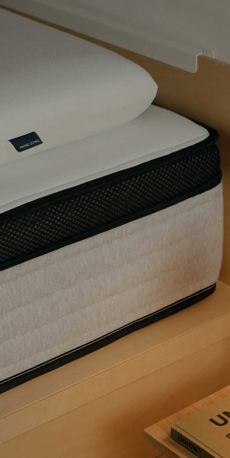 一個附有 Awake Living 品牌標籤的枕頭,放置在床墊的角落。