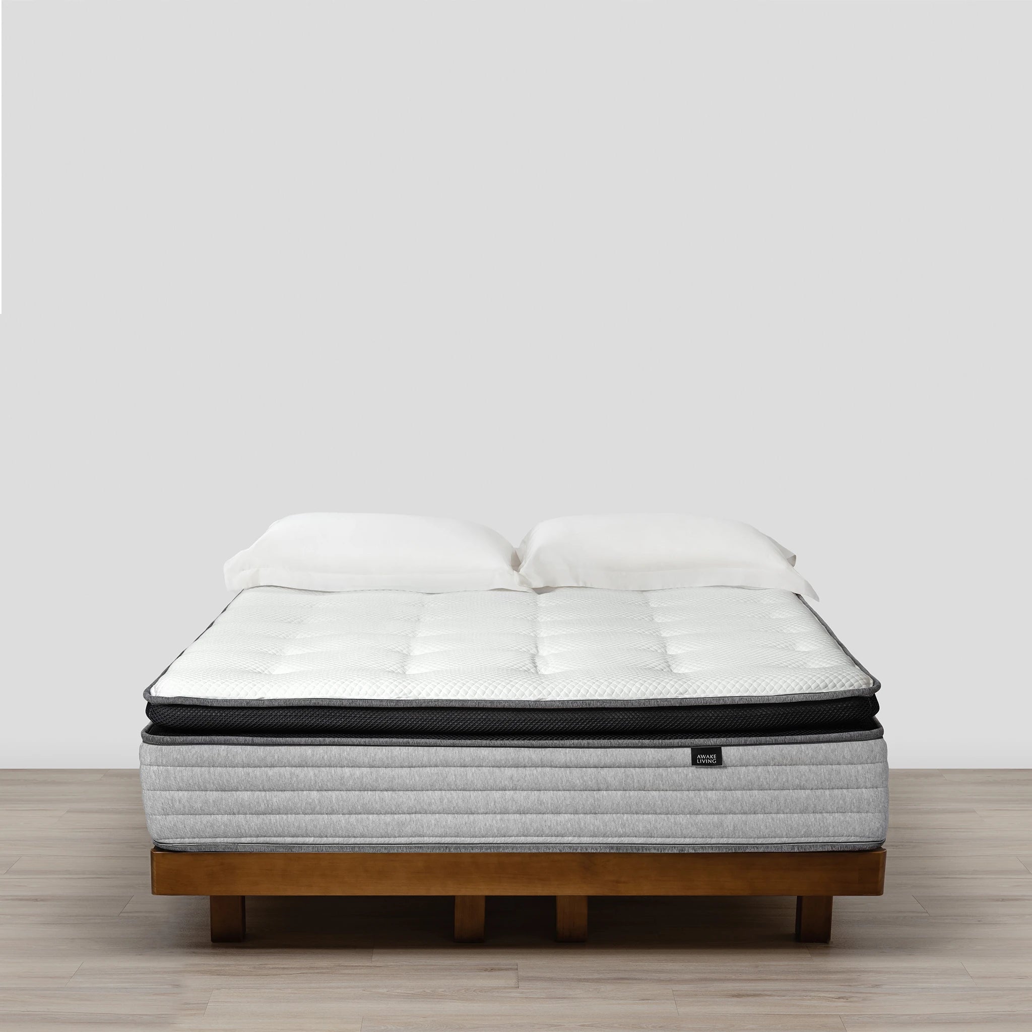 Premium 2.3 床墊置於木質床架上,並搭配兩個白色枕頭。