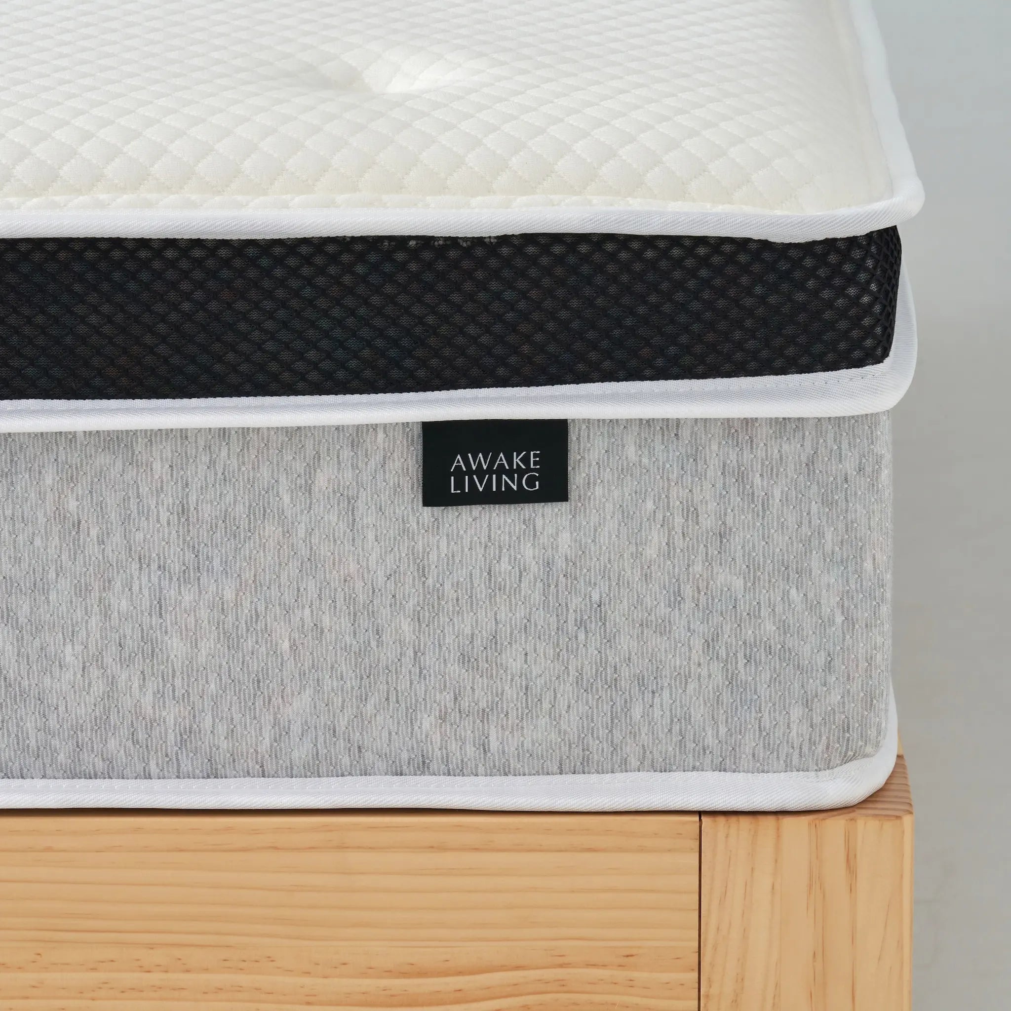 Rigid 2.4 床墊的側面特寫,聚焦於品牌布標、灰色布料與黑色網眼飾帶。