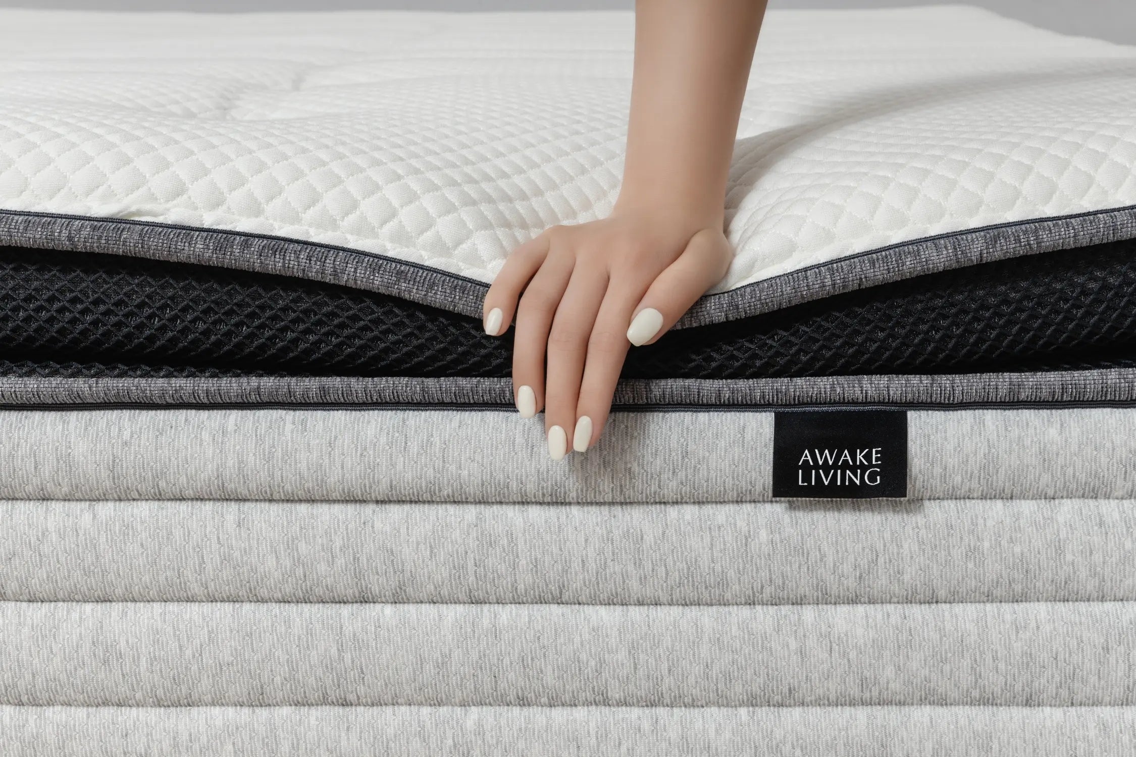 手掌輕壓在 Premium 2.3 零壓深眠床墊表面,展現床墊柔軟與回彈的支撐手感。白色立體菱格天絲表布搭配中層黑色透氣網布與灰色混紡包邊,結構分明,細膩的層次設計強調高支撐與透氣兼備的睡眠體驗,營造出靜謐沉穩的氛圍。