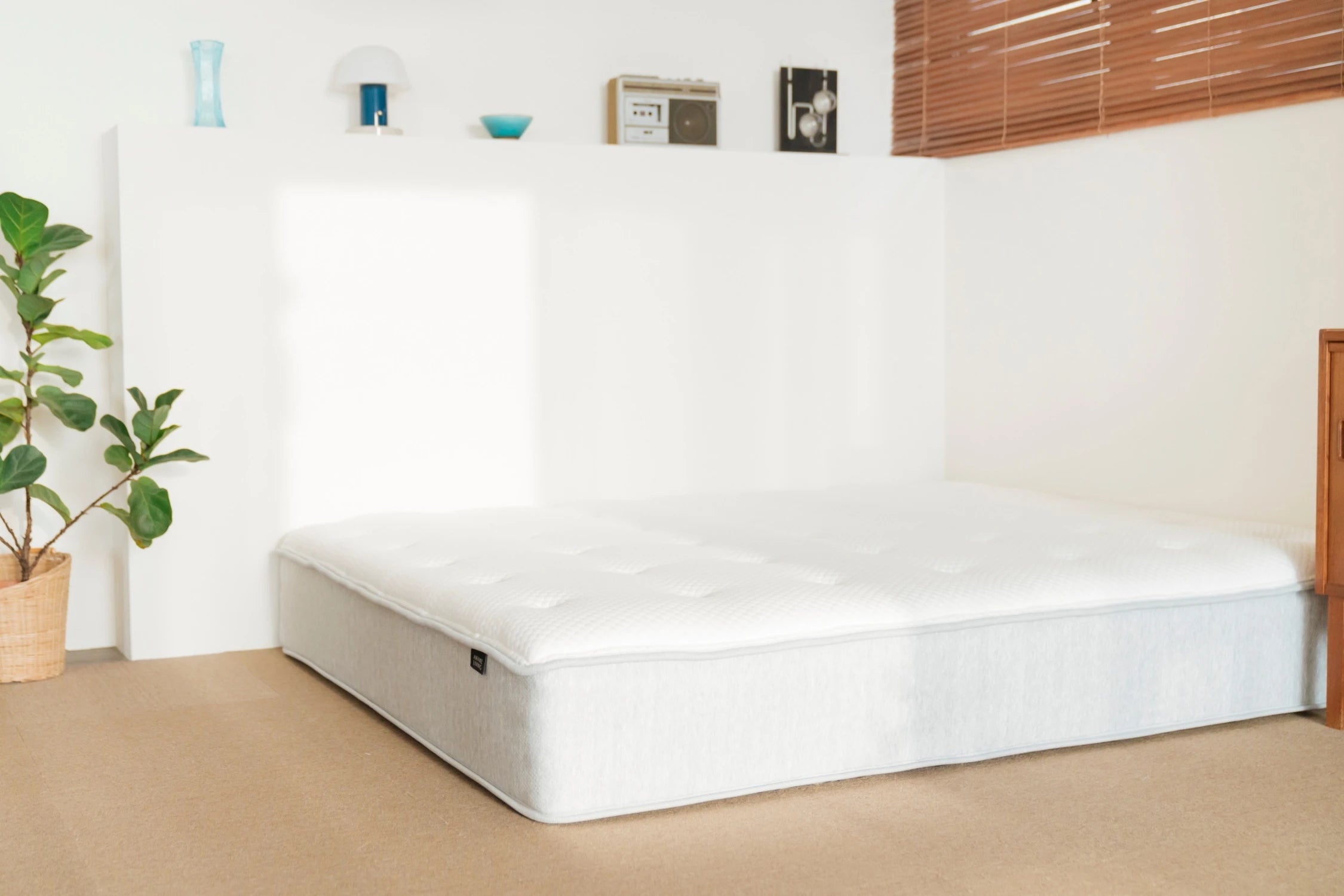 Elite 2.0 床墊直接放置在臥室地板上,後方矮牆上擺有裝飾品。