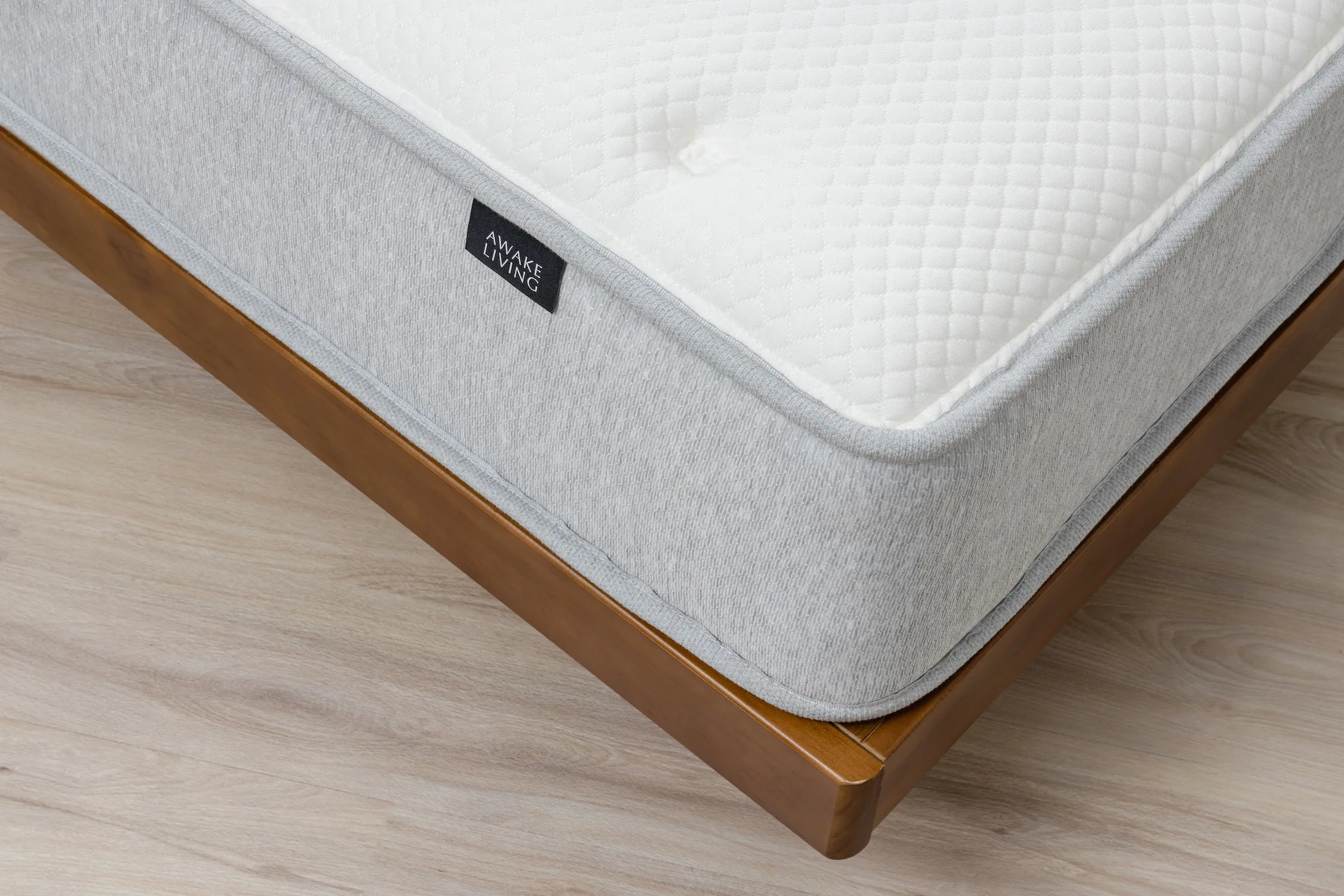 Elite 2.0 床墊的角落俯視圖,展示其床面與灰色床邊,並置於木質床架上。