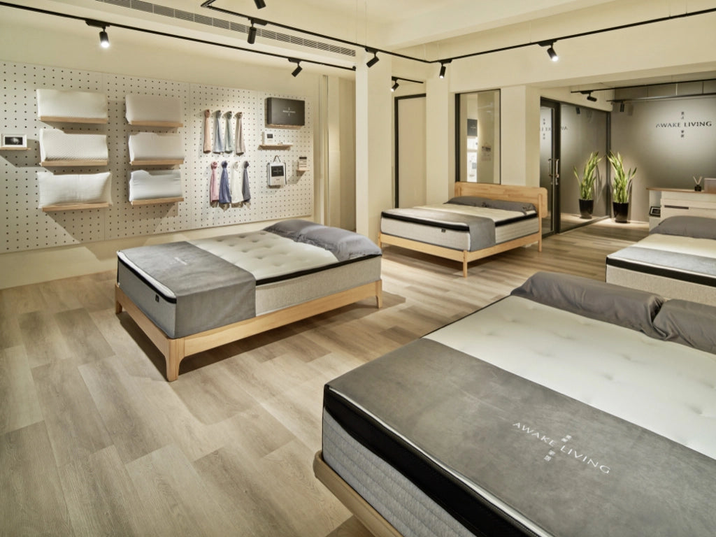 Awake Living 門市內部陳設，空間中展示多張床墊以及牆上的產品陳列區。