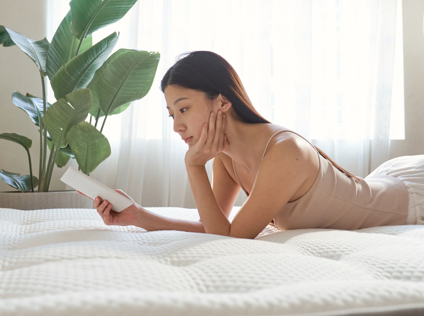 一位女性趴在覺醒家居 Original 經典好眠床墊上手拿著書本在看書