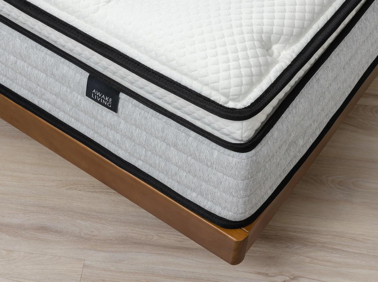 Deluxe 床墊以俯視角 45 度放置在實木床架上，圖中呈現菱格表布紋理以及正三線圍邊造型。