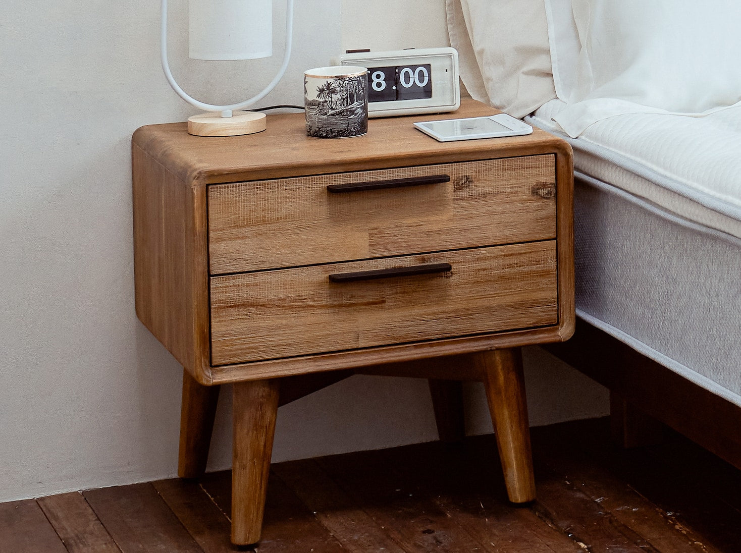 覺醒家居的木質床頭櫃放置在覺醒家居 Original 床墊旁，床頭櫃上方放了鬧鐘和小檯燈